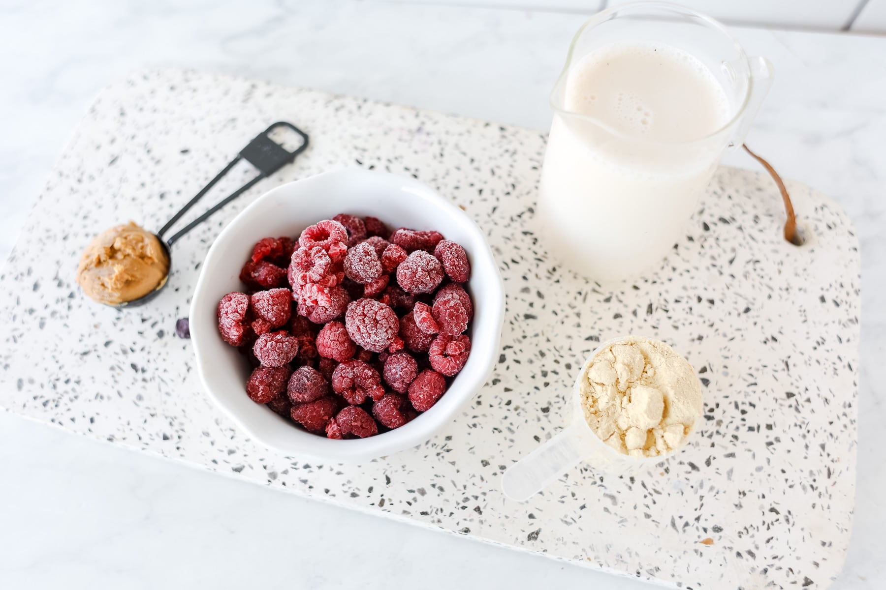raspberry smoothie ingredients on a white cutting board