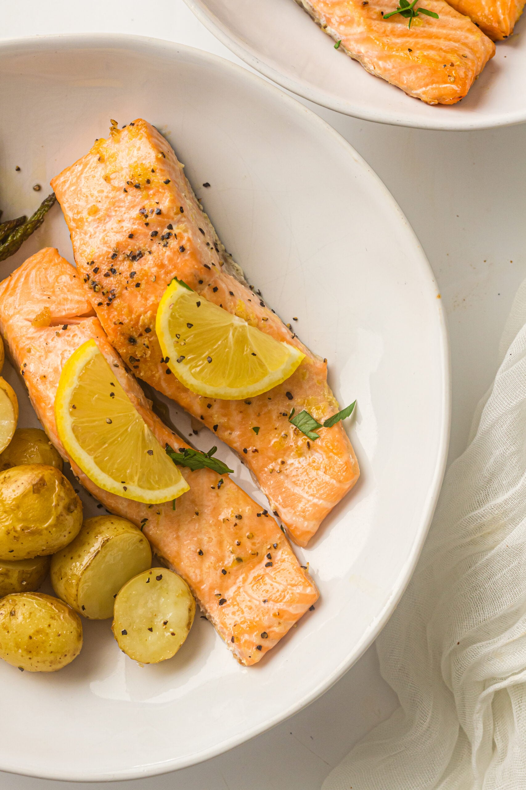 two pieces of salmon with baby potatoes on a white plate
